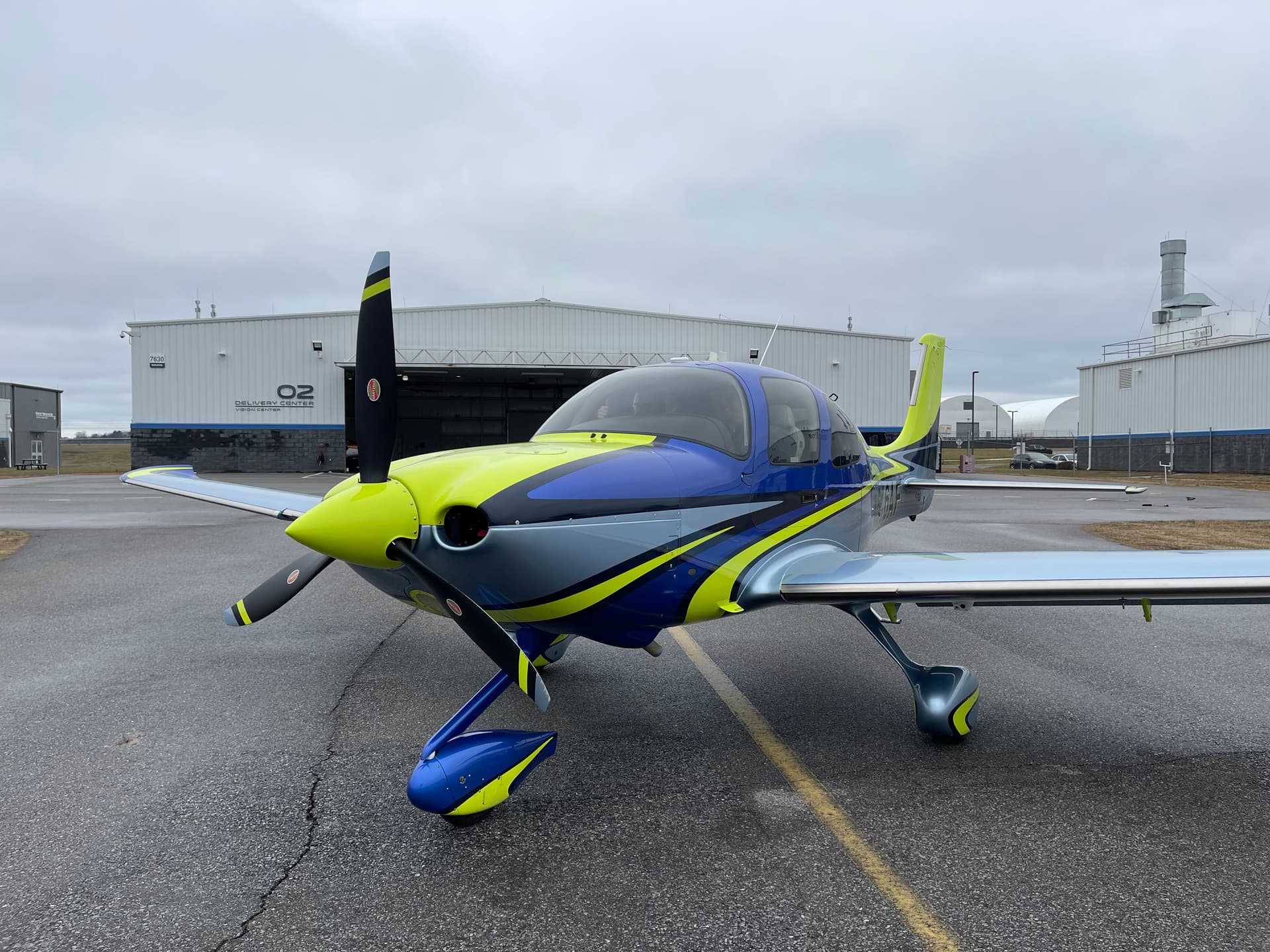 A Cirrus SR22 in blue, gray and lime livery on the ramp in front of the hangars at Grand Strand Airport