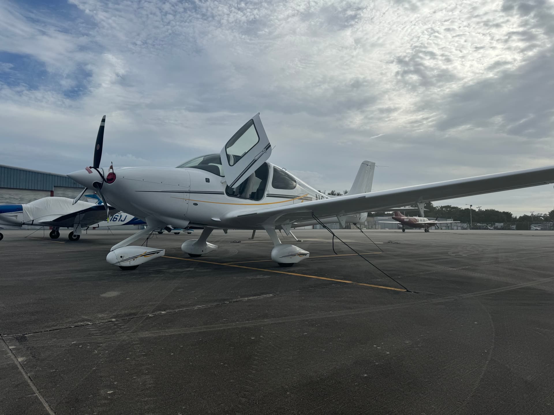 A white Cirrus SR20 with its cabin door raised, parked on the ramp at Grand Strand Airport